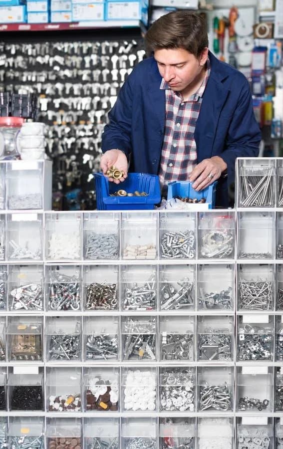 A hardware shop worker sorting fittings behind a counter